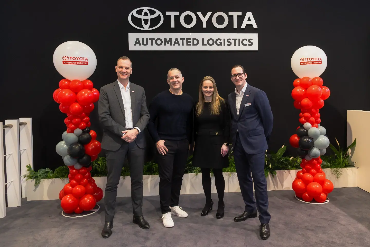 Four persons in front of a Toyota Automated Logistics sign at Logimat.