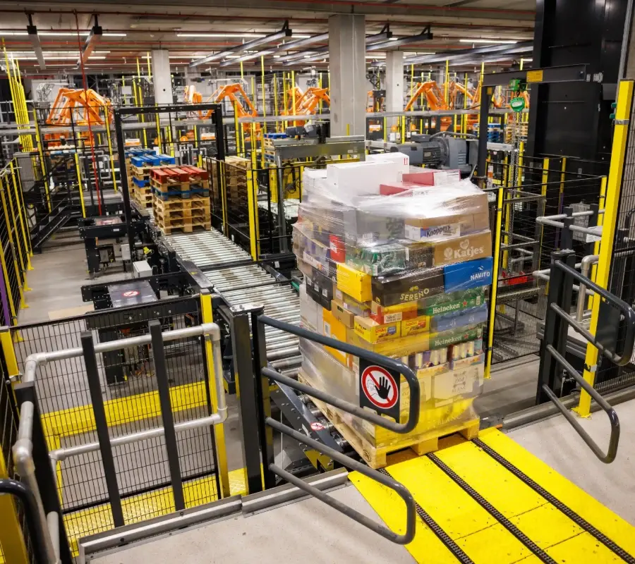 Automated conveyor system moving a shrink-wrapped pallet through an industrial distribution center facility.