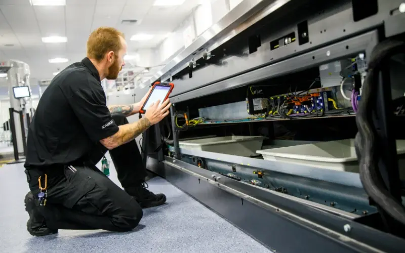 technician-inspecting-security-scanner-with-tablet