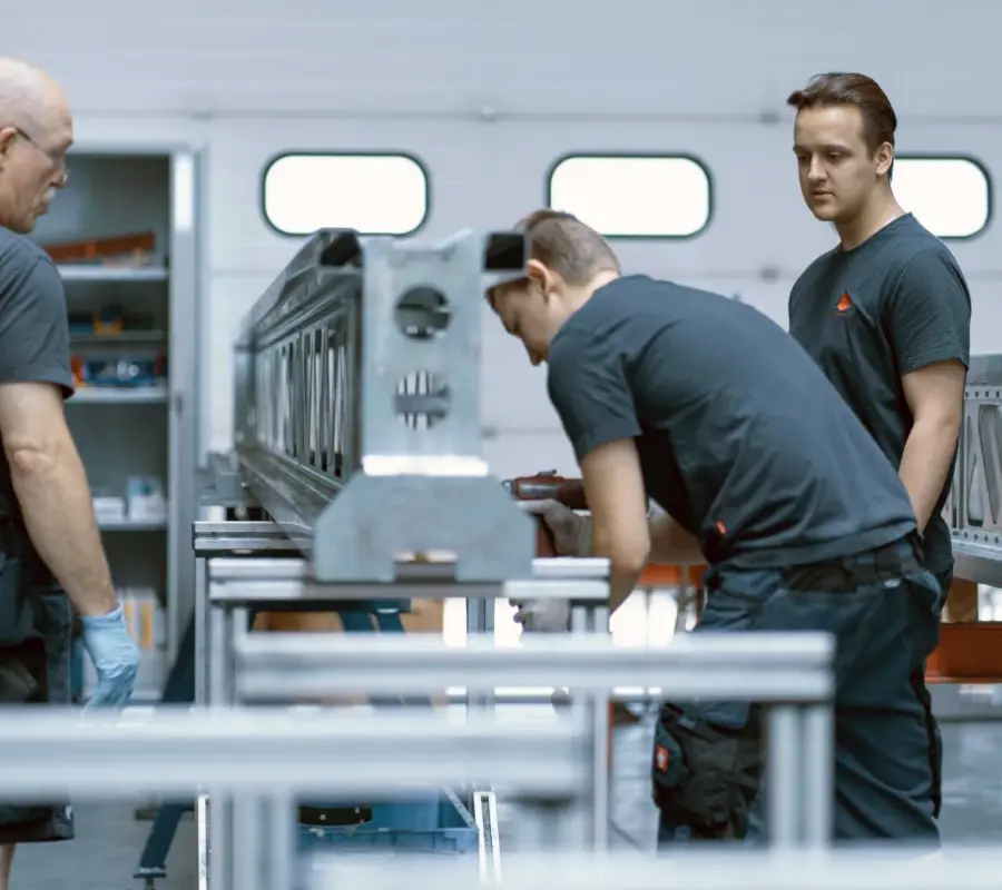 Technicians assembling automated warehouse components in a modern manufacturing facility.