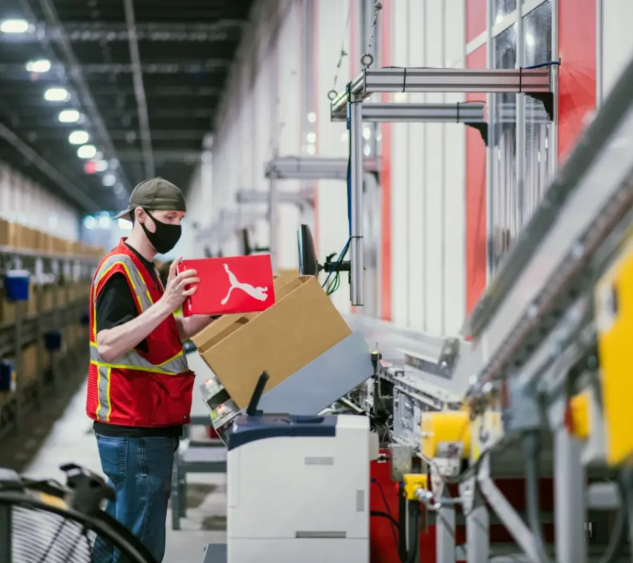 Warehouse worker picking a fashion order at an automated picking station.