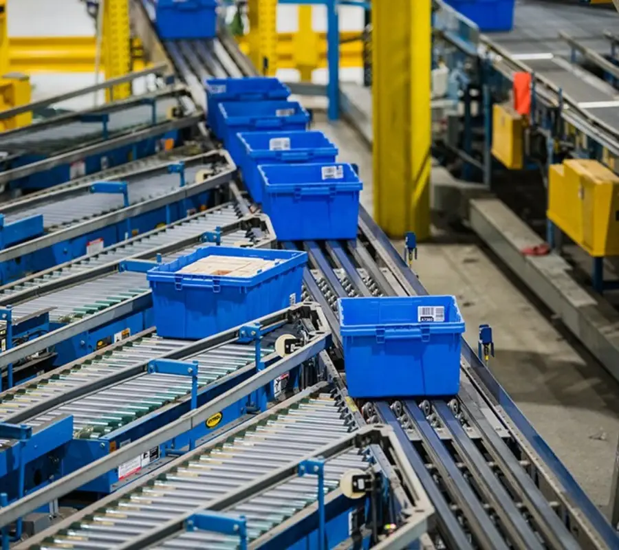 Automated sortation system transporting blue storage bins in a parts and components warehouse.
