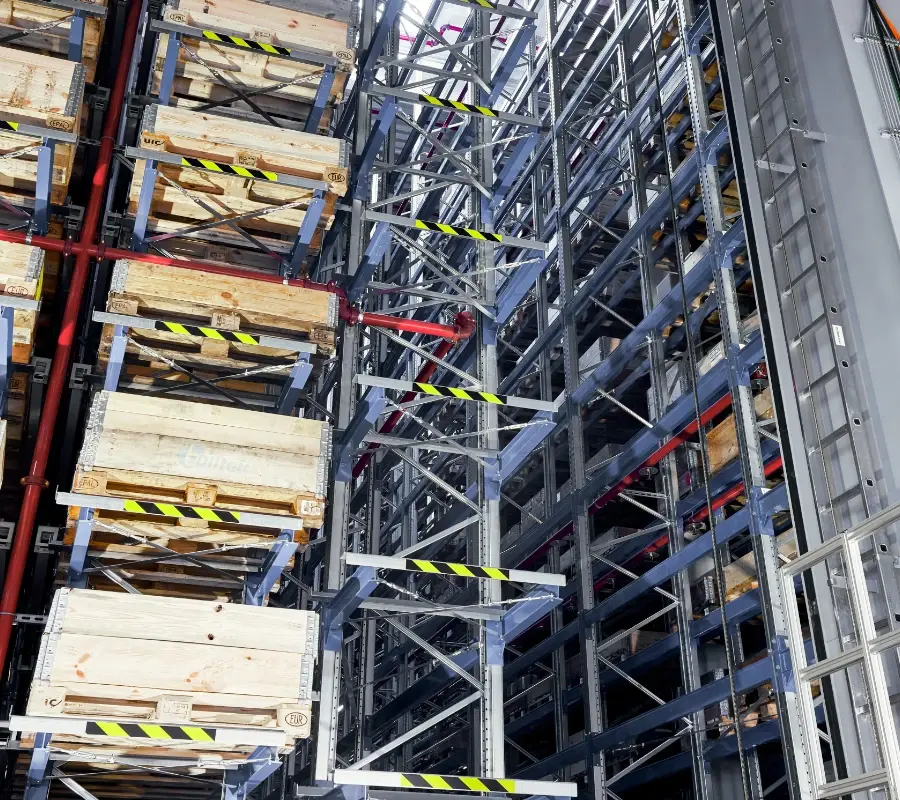 Automated storage and retrieval system (ASRS) featuring high-density pallet racking and wooden crates.