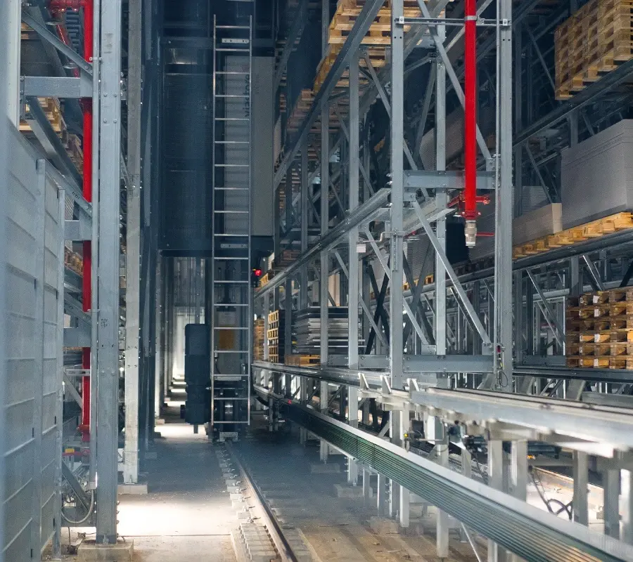 Automated pallet storage and retrieval system (ASRS) with tall metal racking and industrial lift in a warehouse.