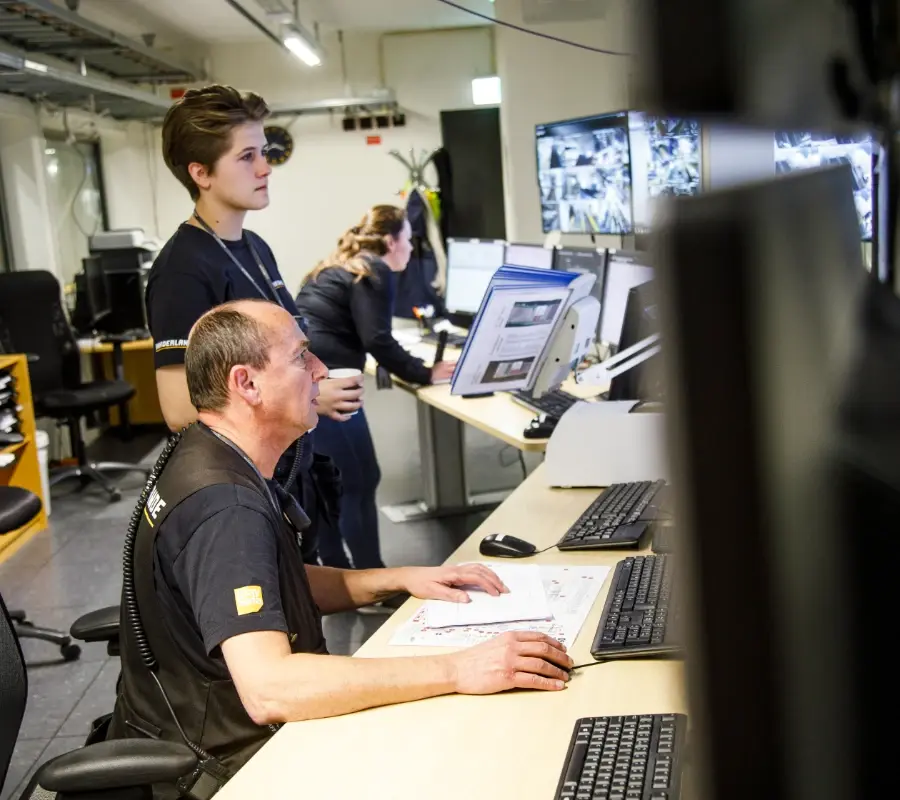 Technicians monitoring automated warehouse systems from a central control room.