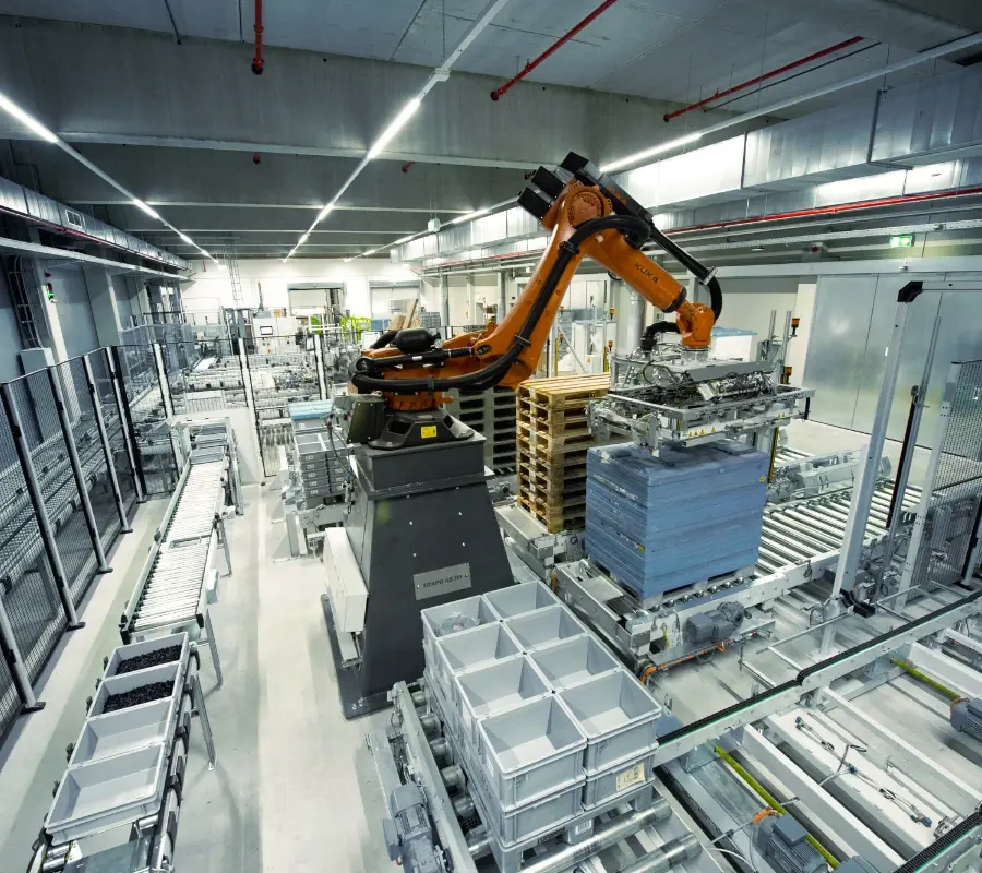 Industrial robotic arm palletizing blue boxes on a conveyor system in an automated warehouse.