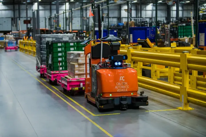 automated guided vehicle towing industrial carts through a modern manufacturing warehouse.