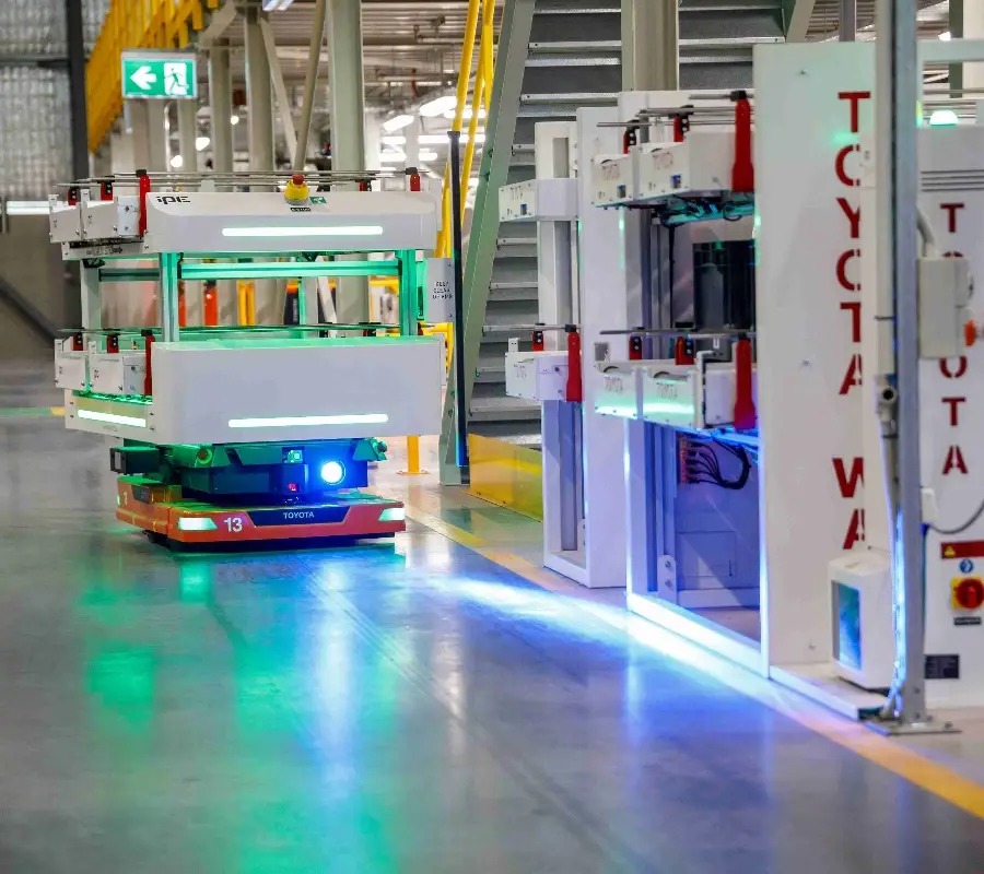 Toyota autonomous mobile robot navigating a warehouse floor using advanced sensors and lighting.