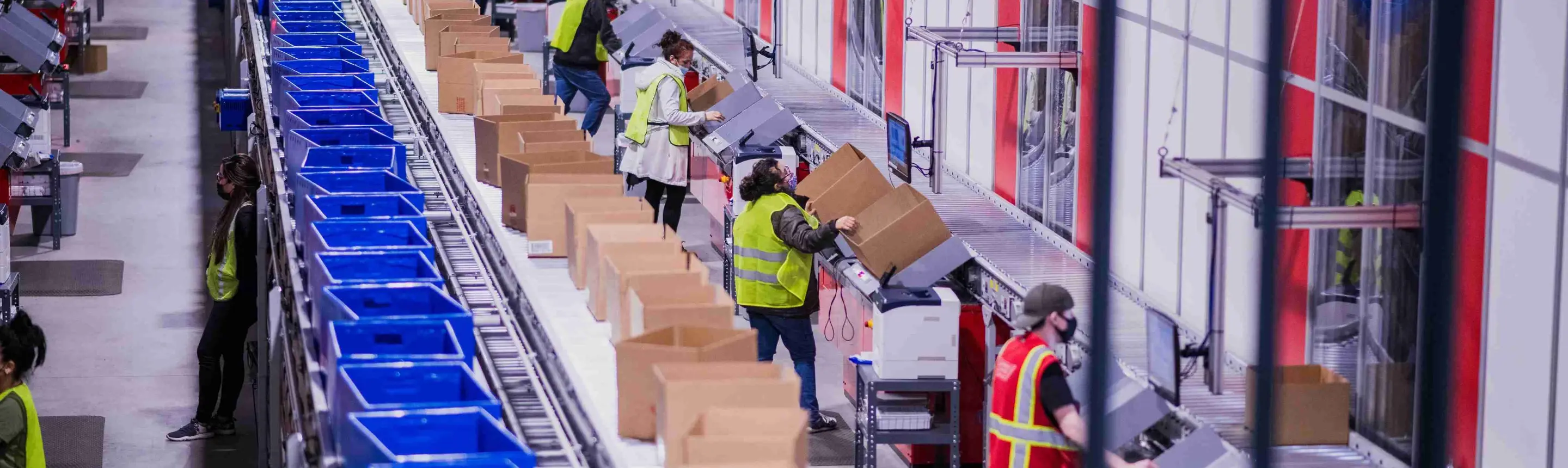 Worker at an automated goods-to-person picking station in a modern warehouse facility.